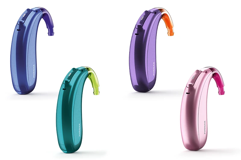 Quatro aparelhos auditivos retroauriculares infantis da linha Phonak Sky em cores vibrantes (azul, verde-água, roxo e rosa), desenvolvidos para o conforto e segurança de bebês e crianças pequenas.